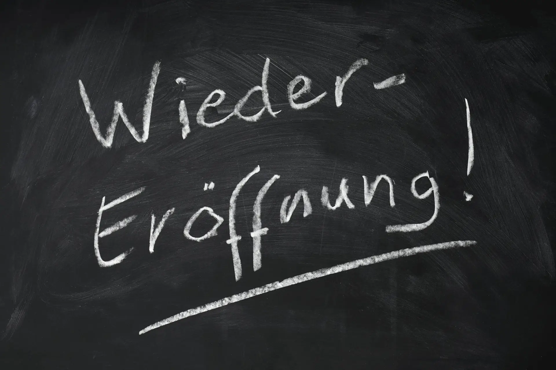 Wiedereroeffnung means reopening in German - handwritten text on chalkboard